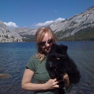 Lady with small dog by lake